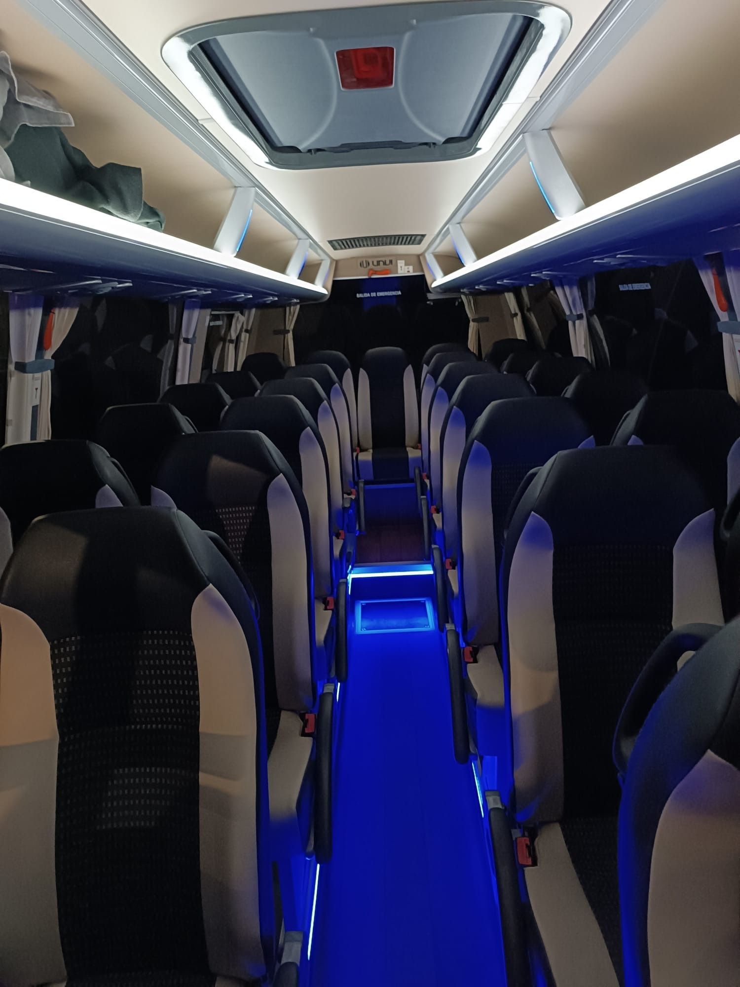 El interior de un autobús con luces azules en los asientos.