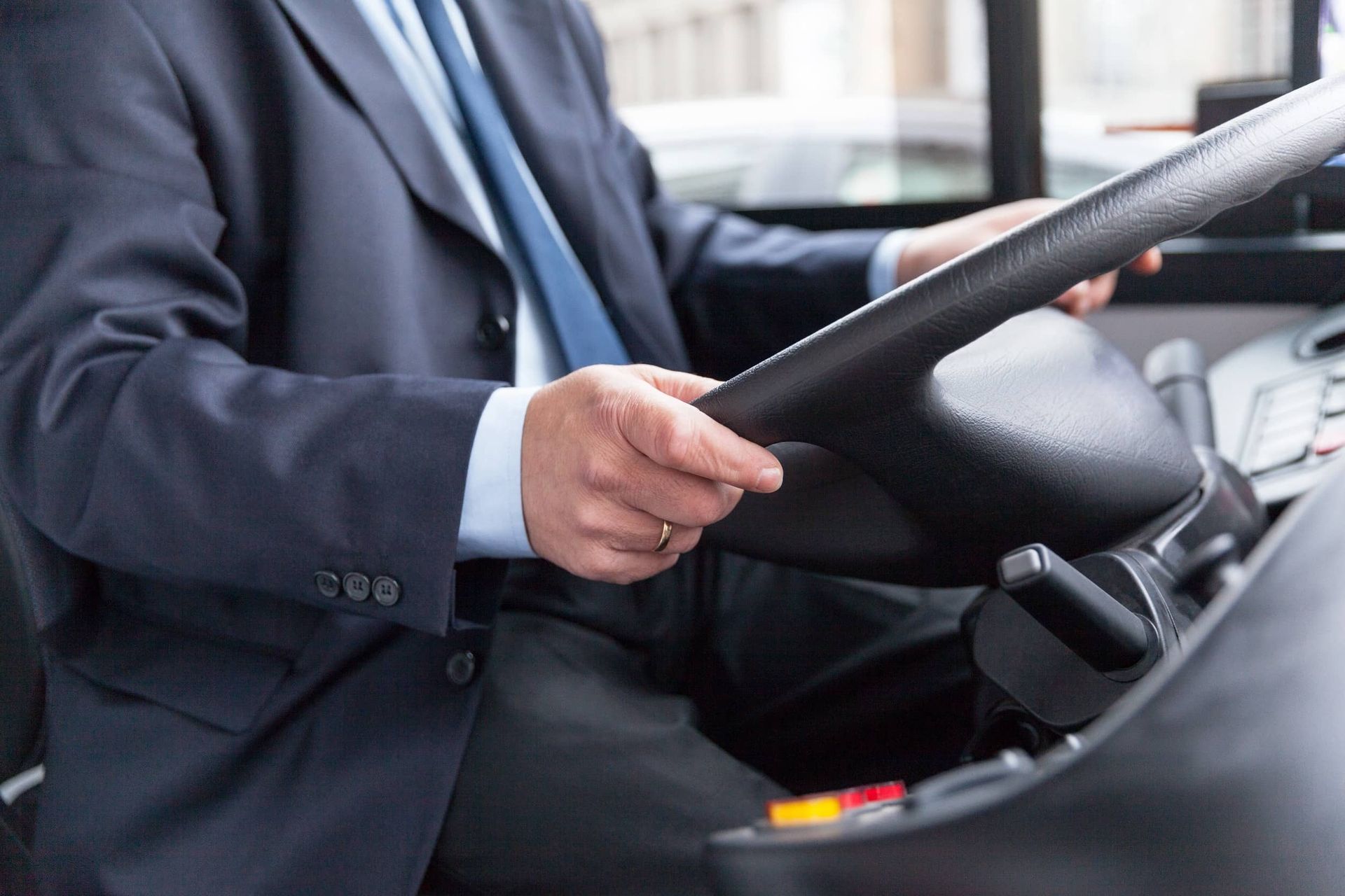Un hombre con traje y corbata conduce un autobús.