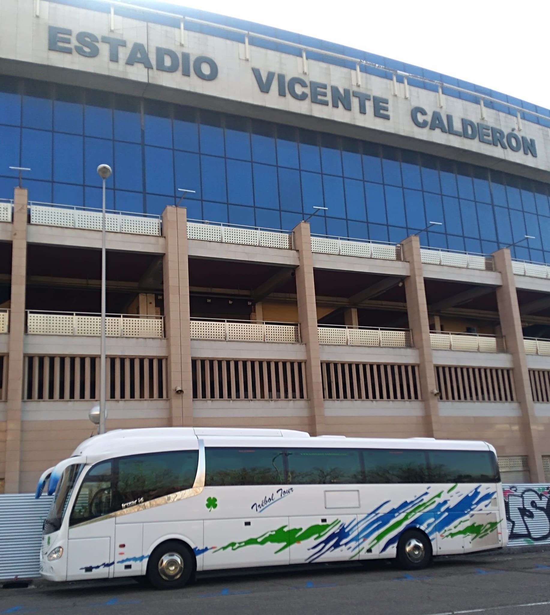 Un autobús está estacionado frente a un edificio que dice Estadio Vicente Calderón.