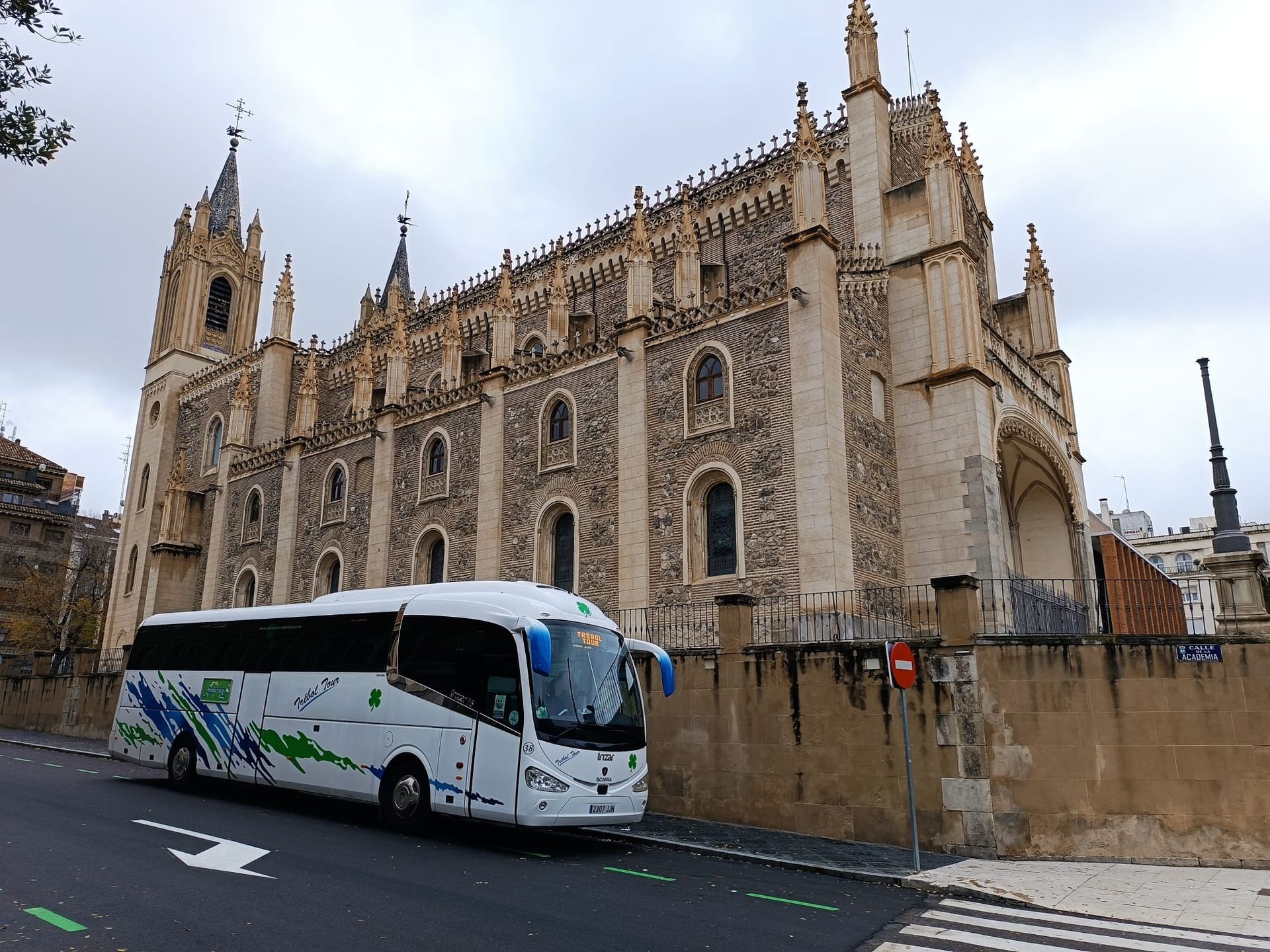 Un autobús blanco está estacionado frente a un gran edificio.