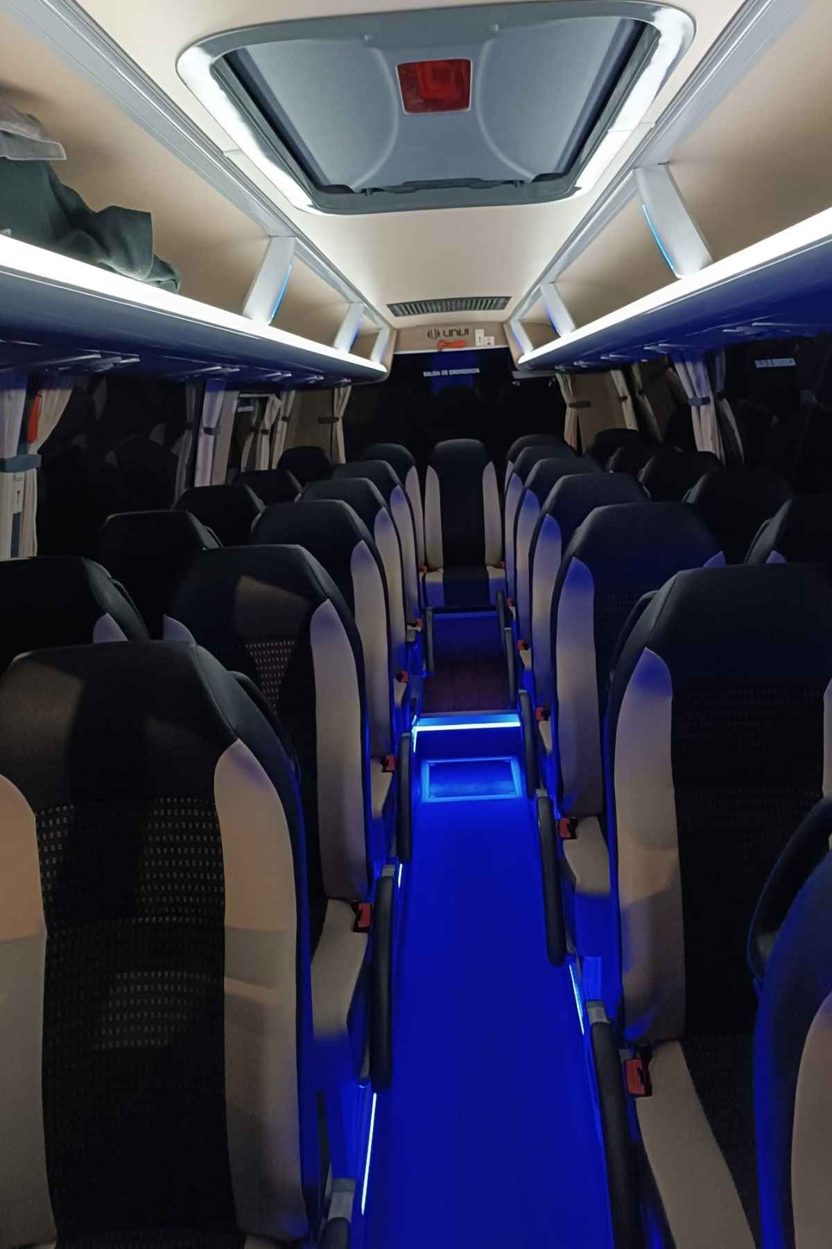 El interior de un autobús con luces azules en los asientos.