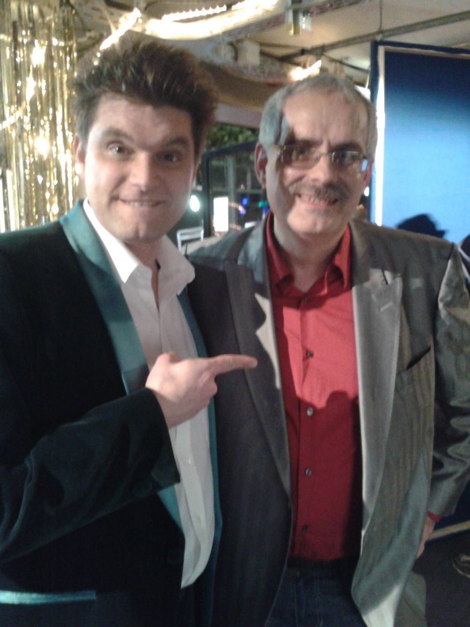 Zwei Männer posieren für ein Foto und einer zeigt in die Kamera