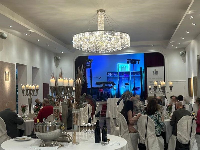 Ein großer Raum mit Tischen und Stühlen und einem Kronleuchter, der von der Decke hängt.