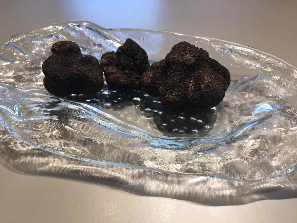 Tres trufas de chocolate negro en un plato de cristal transparente