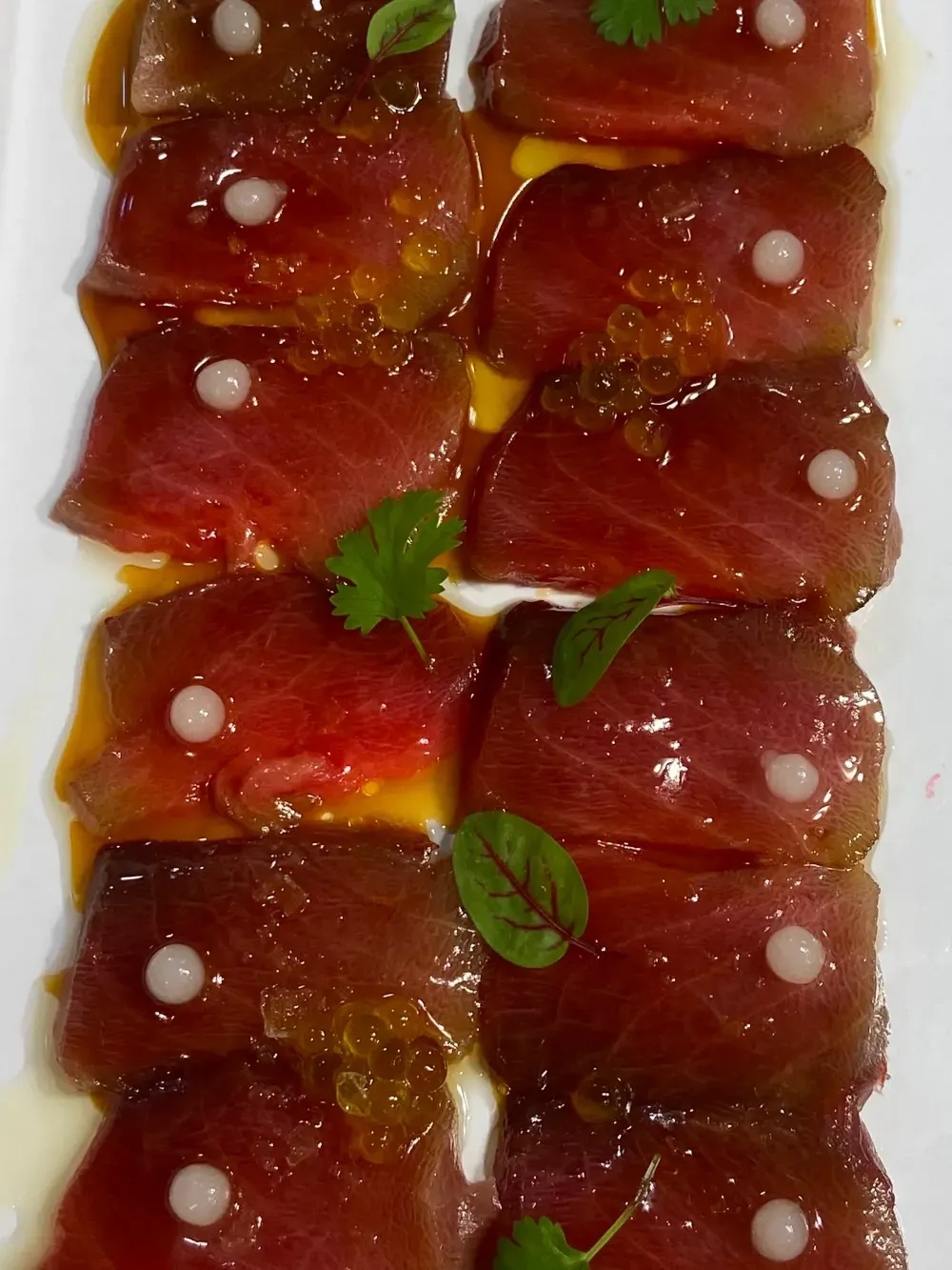 Postres de gelatina roja apilados, con puntos blancos y hojas de menta verde, servidos en un plato