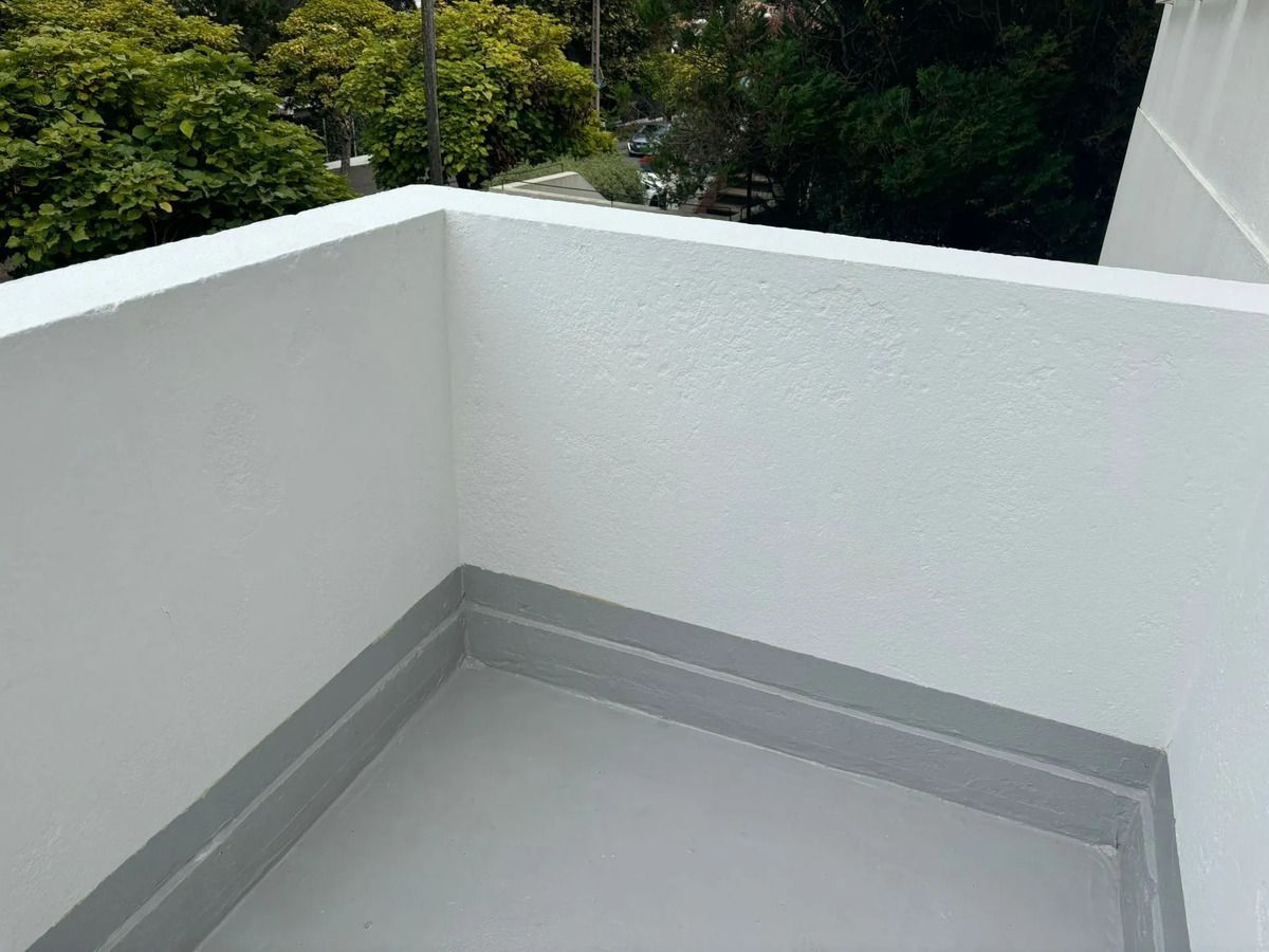 Persona caminando sobre el césped hacia una casa de ladrillo con cochera; día nublado.