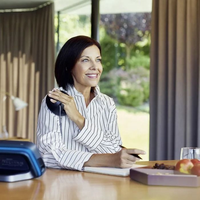 Une femme en chemise rayée est assise à un bureau