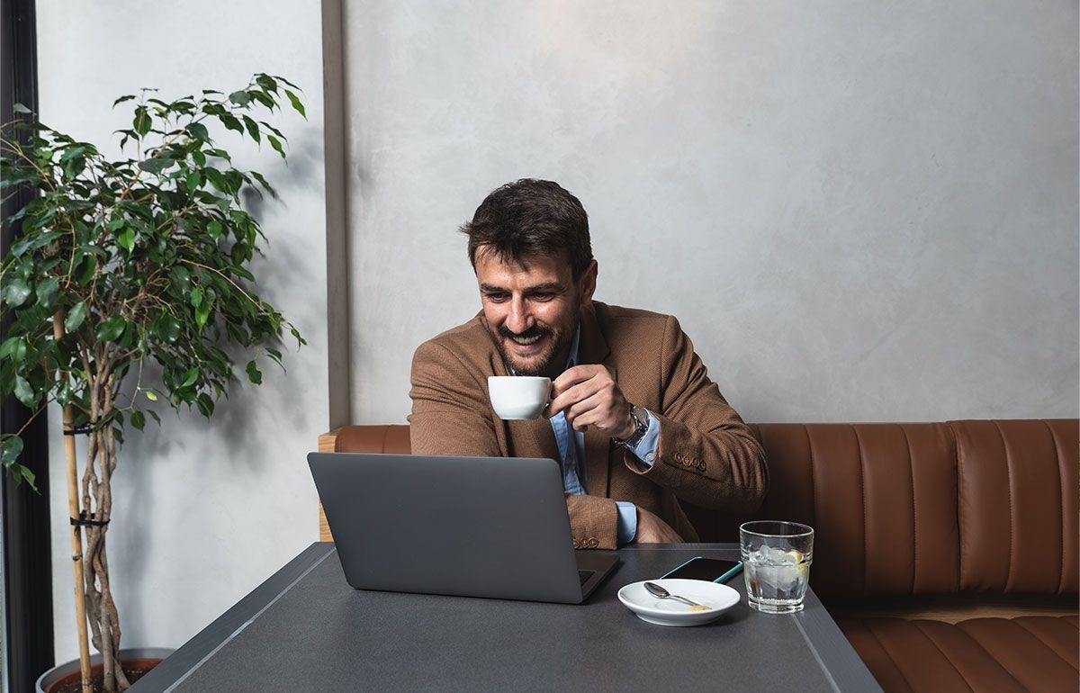 Homme buvant un café derrière un écran d'ordinateur