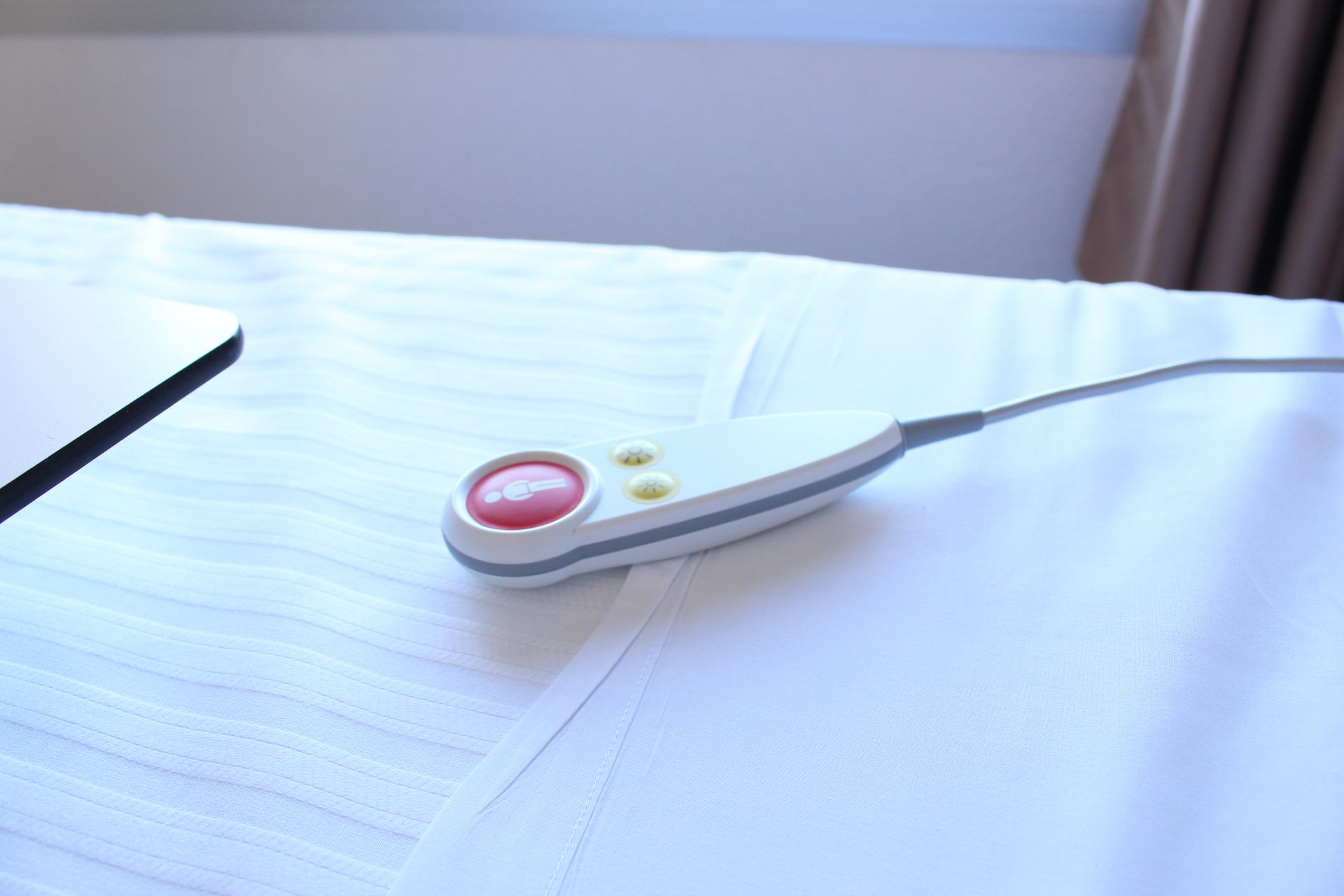 Bouton d'appel infirmière sur draps blancs.