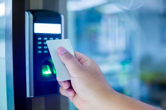 Il passe sa carte d'accès sur un système de sécurité pour déverrouiller la porte.