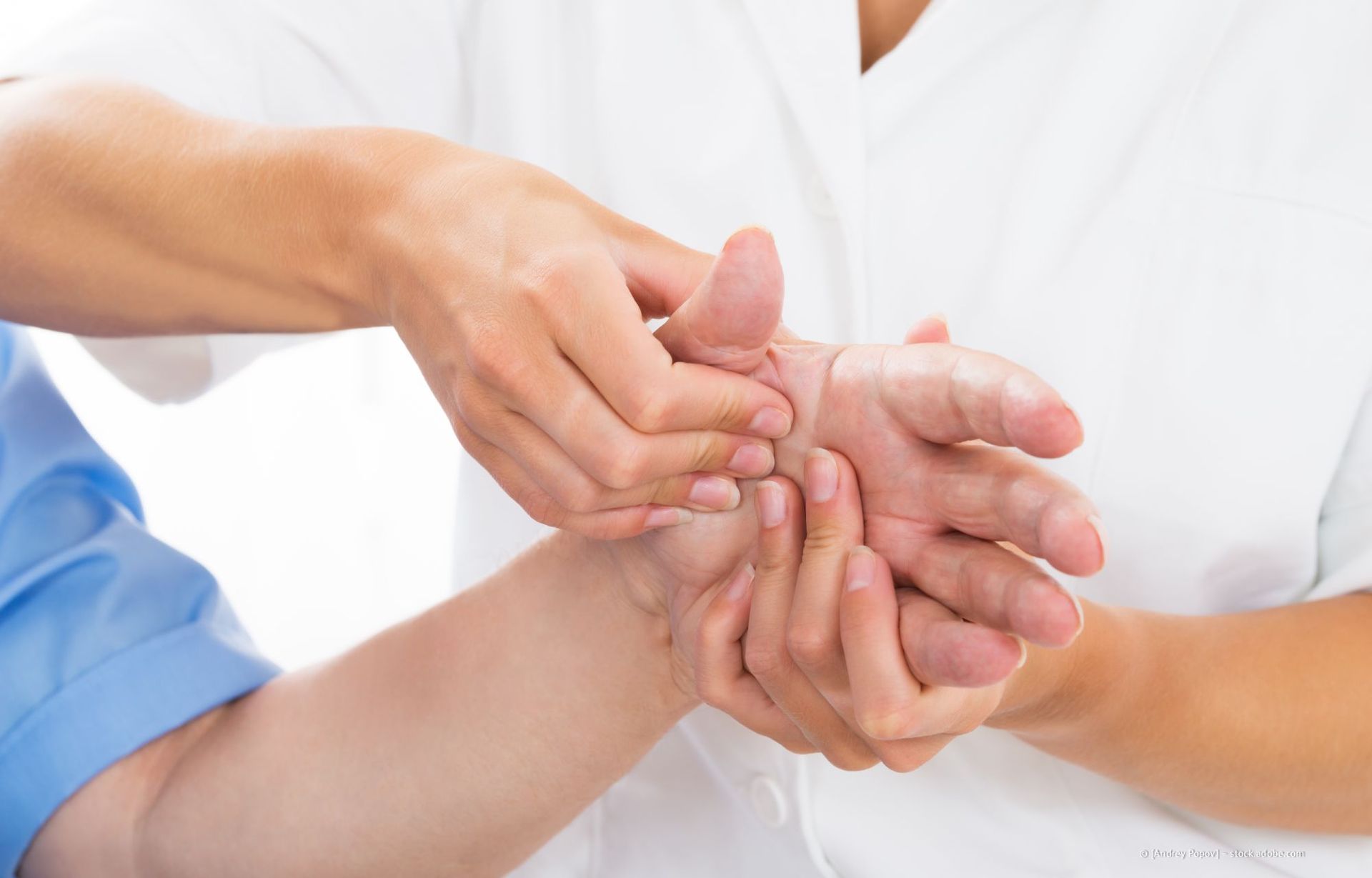 Die Hände einer Person, die Physiotherapie erhält; eine andere Person massiert die Handfläche.