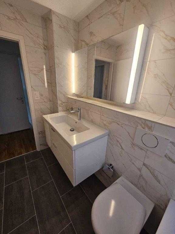 Freiliegende Stromkabel hängen von einer beschädigten Decke herab. In der unteren linken Ecke befindet sich ein Fenster.