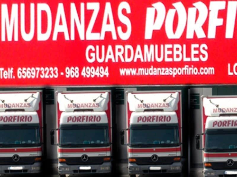 Varios camiones están estacionados frente a un cartel que dice mudanzas porfi