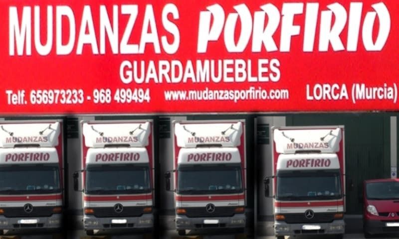 Varios camiones están estacionados debajo de un letrero que dice mudanzas porfirio