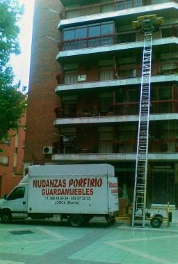 Un camión blanco con la palabra mudanzas está estacionado frente a un edificio.