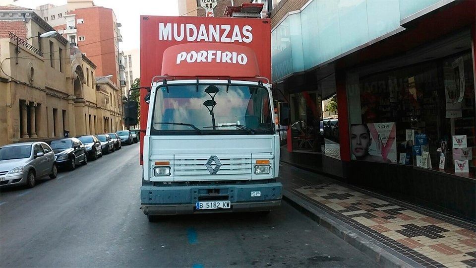 Una camioneta blanca con techo rojo que dice mudanzas porfirio