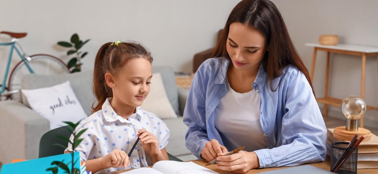 Una mujer está ayudando a una niña con su tarea.