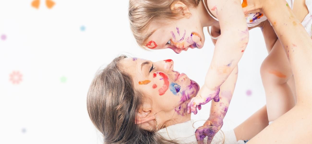 Una mujer sostiene a una niña con pintura en la cara.