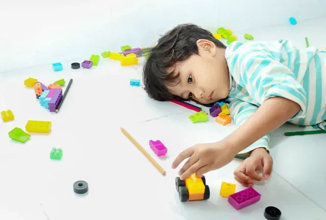 Un niño pequeño está tumbado en el suelo jugando con juguetes.