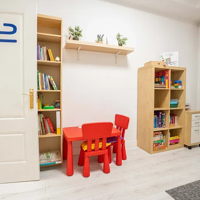 Una habitación infantil con una mesa y sillas rojas.