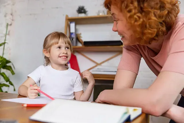 Una mujer está sentada en una mesa con una niña.
