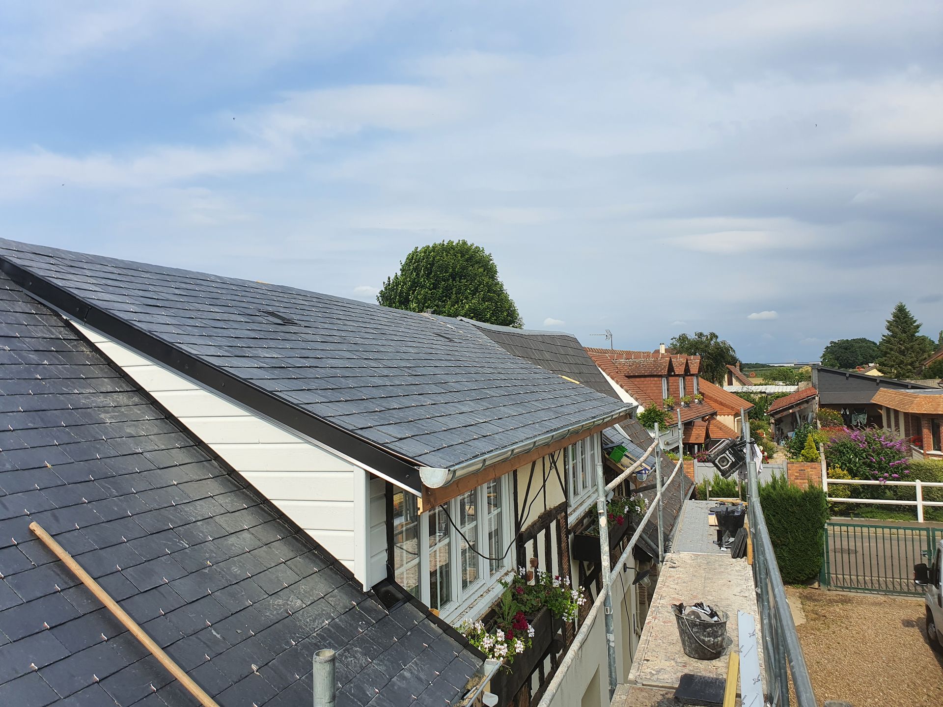 Toits de maisons avec panneaux solaires le long d'un chemin de jardin sous un ciel nuageux