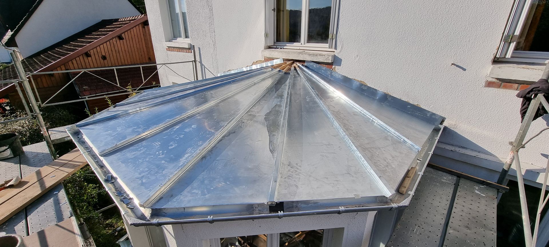 Toiture métallique avec puits de lumière central sur le porche d'une maison, vue de dessus.