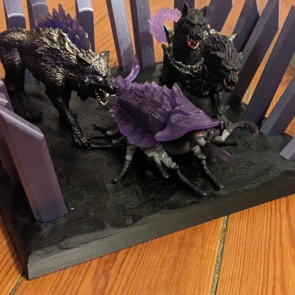 Eine Tischdekoration mit zwei Wolfsfiguren und einem insektenartigen Wesen, alle in dunklen Farben mit violetten Akzenten.