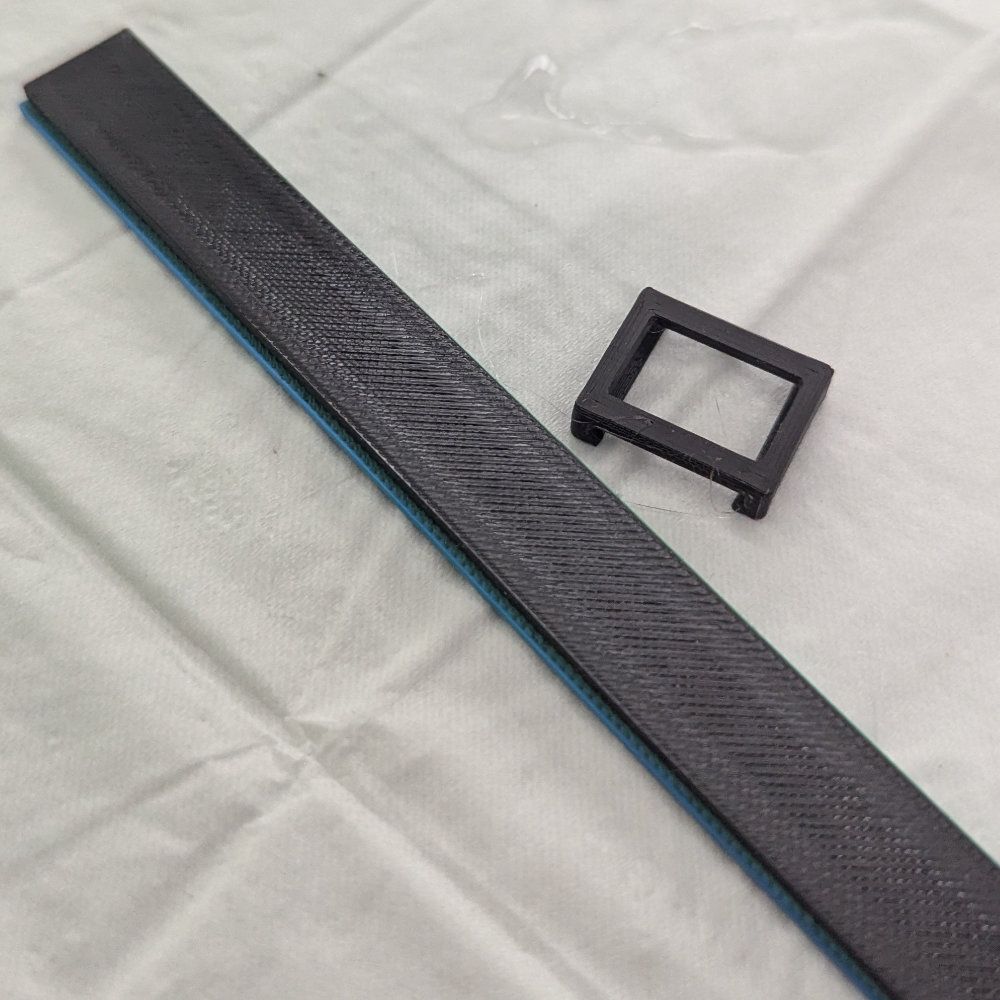 Ein langer, strukturierter, schwarzer Streifen und ein kleiner, schwarzer, quadratischer Rahmen auf hellblau-weißem Grund.