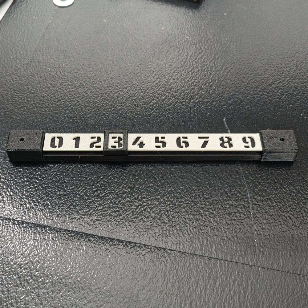 Eine schwarz-weiße Zahlenanzeige mit den Ziffern 0-9. Die Enden haben schwarze Kappen.