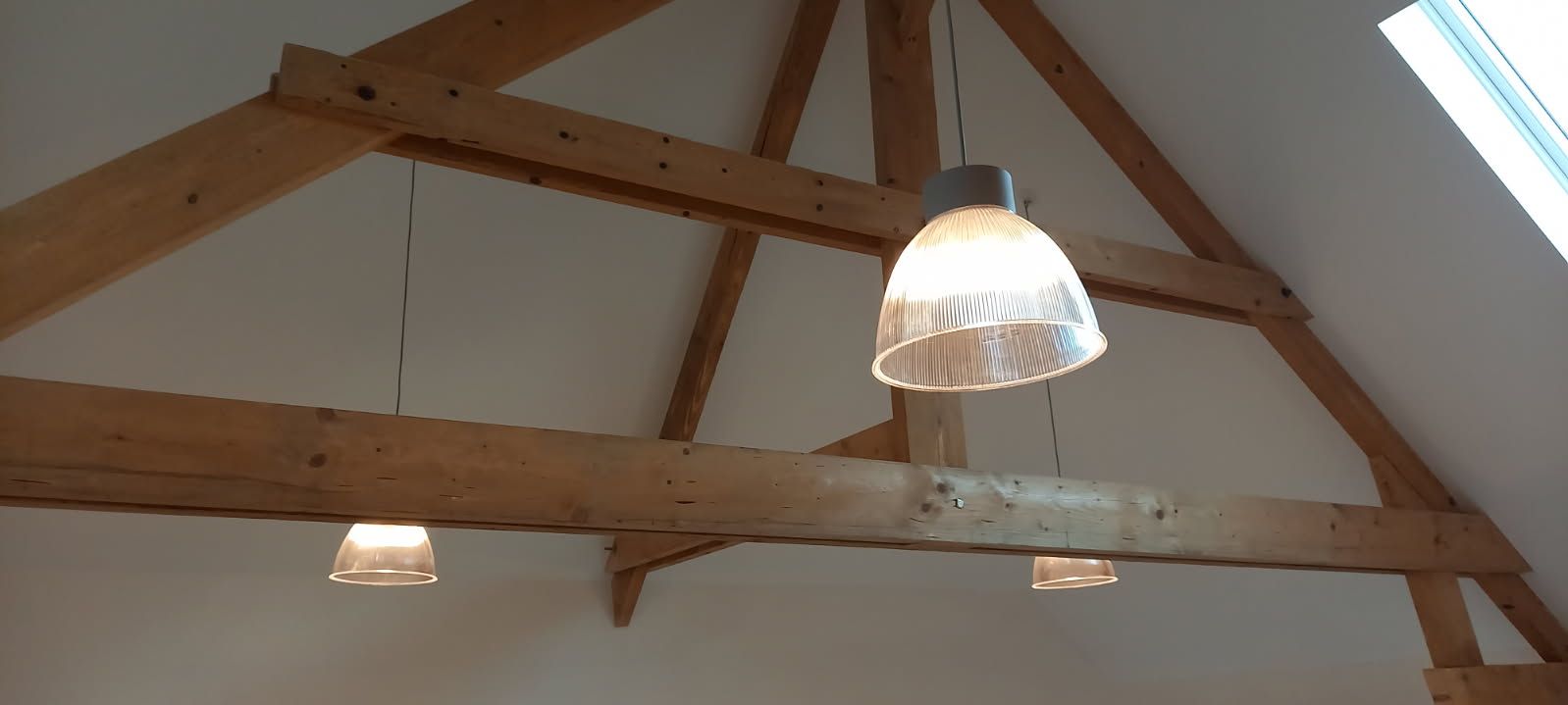 Chevrons en bois avec trois suspensions suspendues sous un plafond blanc.