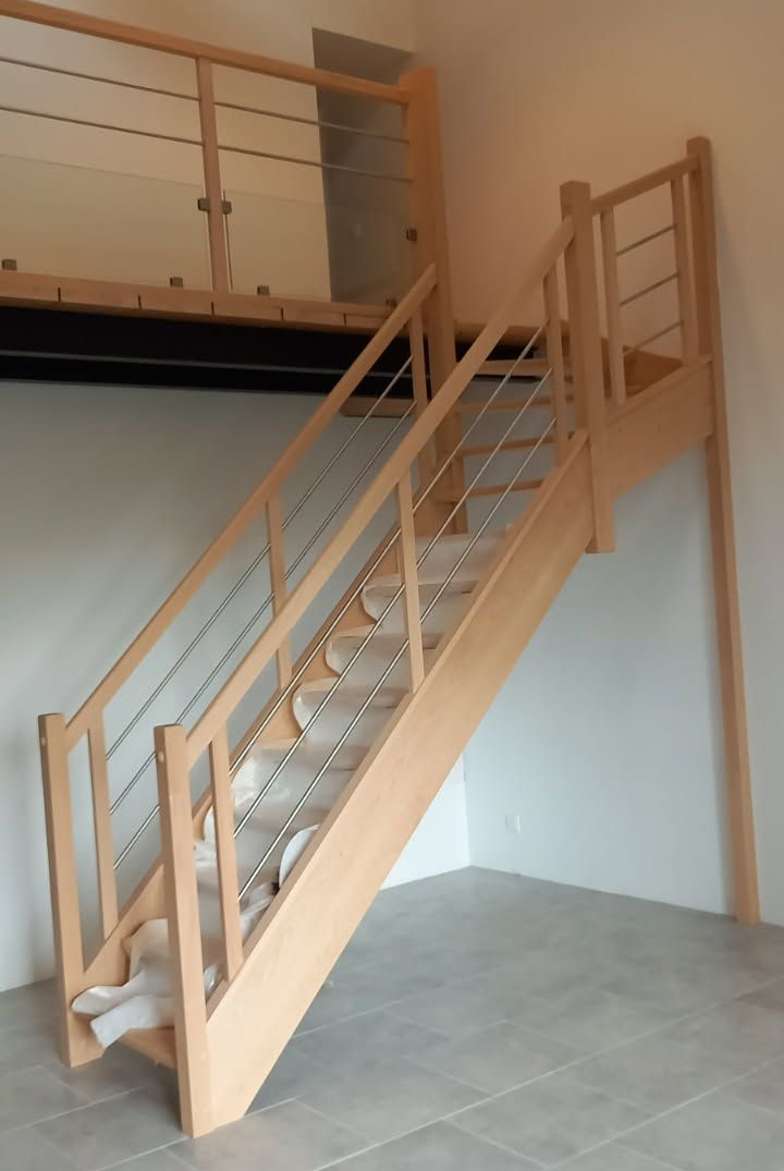 Escalier en bois avec câbles en acier inoxydable et palier, dans une maison moderne.