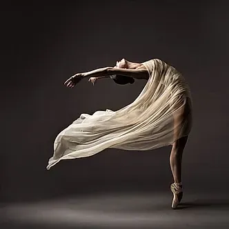 Una bailarina baila con un vestido largo blanco y zapatillas de punta.