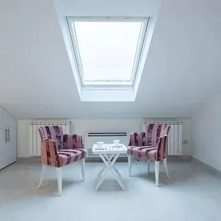 Una sala de estar con dos sillas y una mesa debajo de una claraboya.