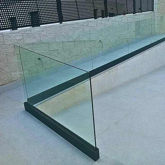 Una escalera con barandilla de cristal y una pared de ladrillos detrás.