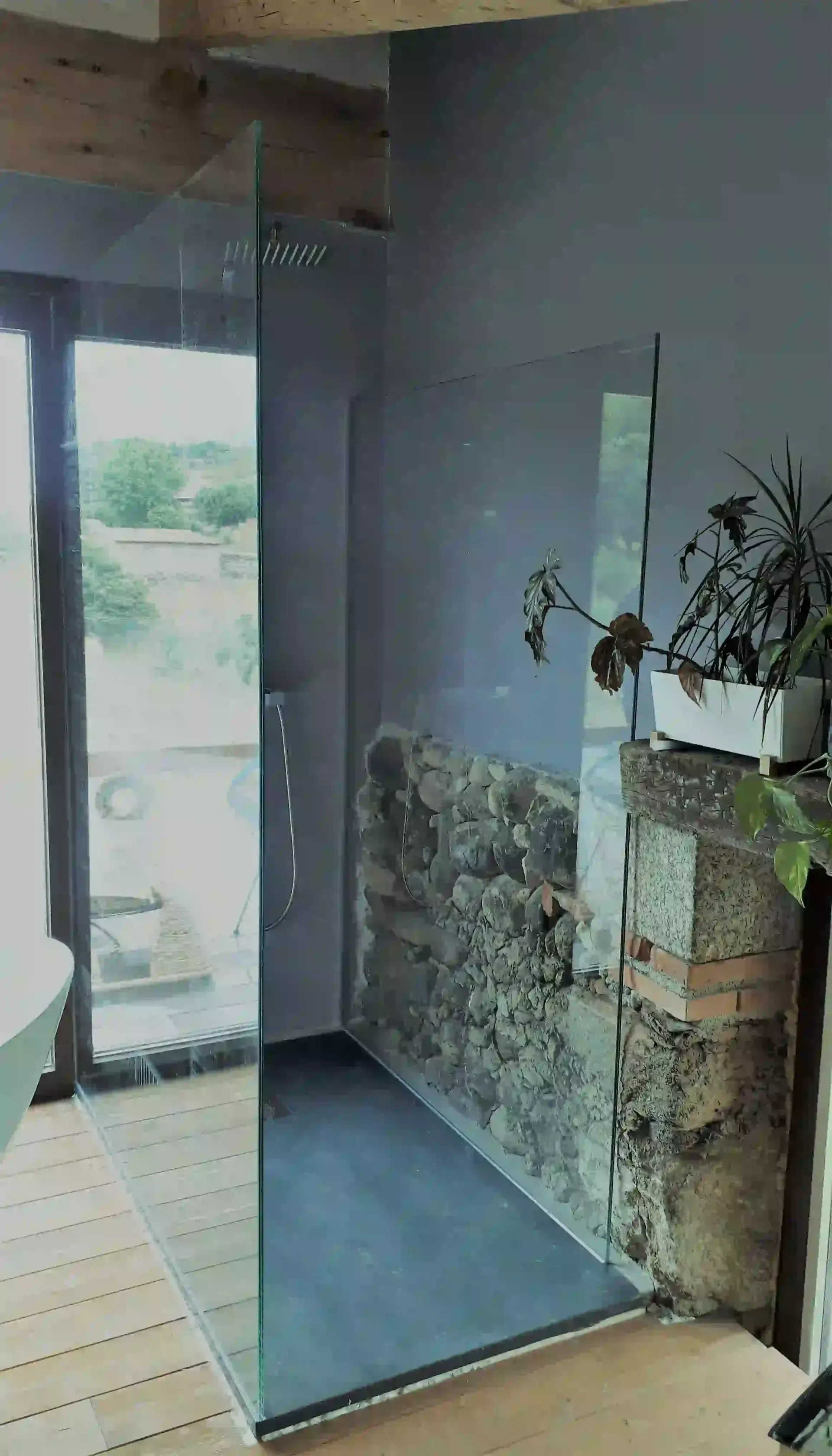 Un baño con ducha a ras de suelo y una pared de piedra.