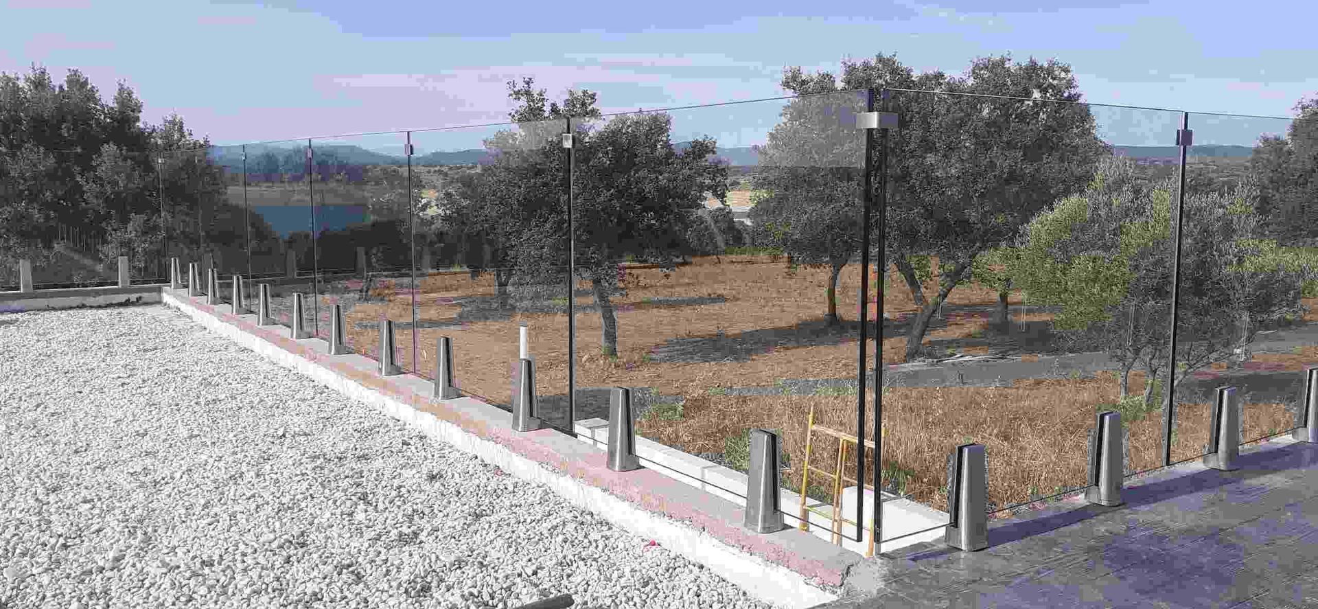 Un camino de grava con una valla y árboles al fondo.