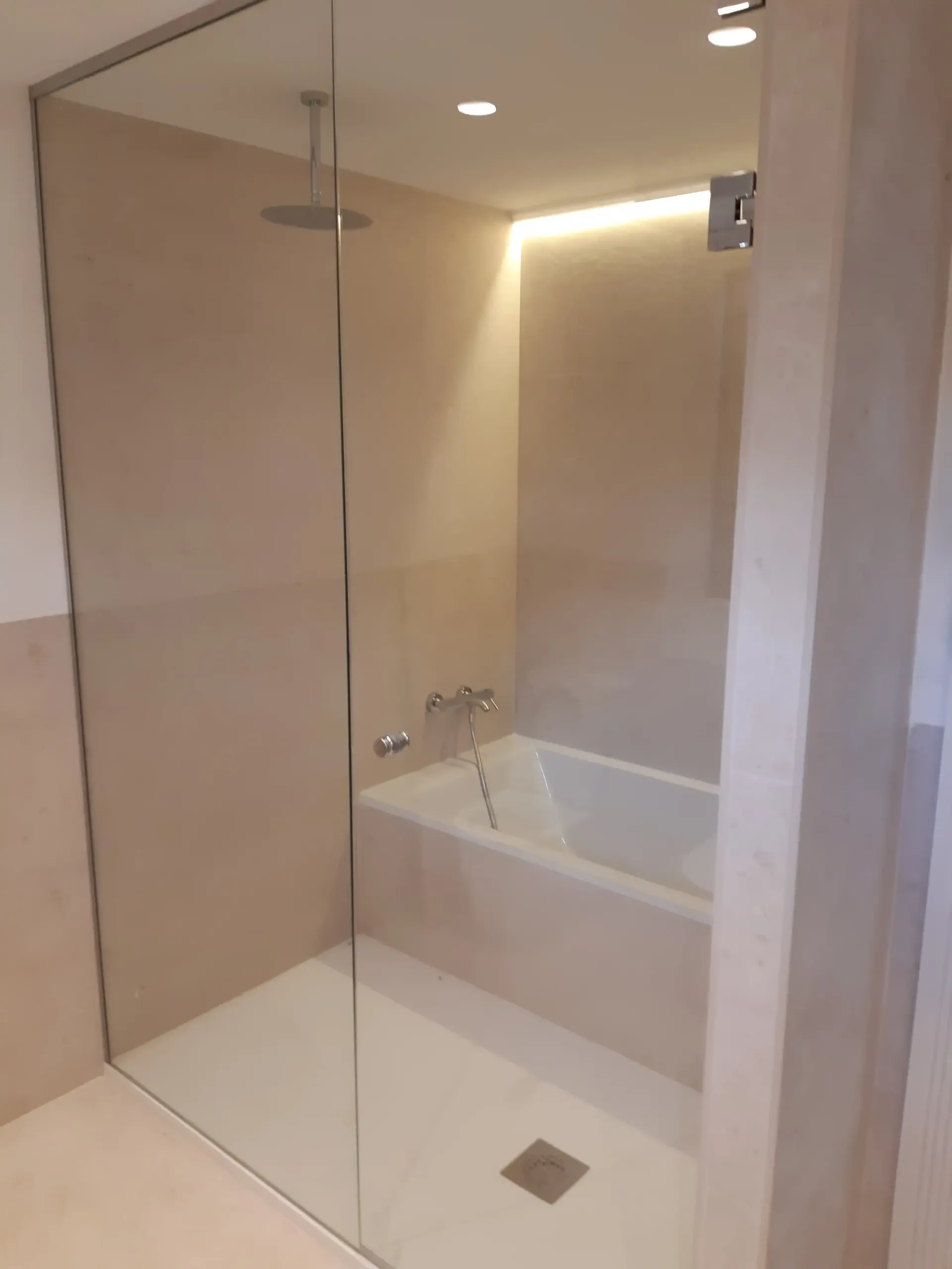 Un baño con bañera y ducha con puerta de cristal.