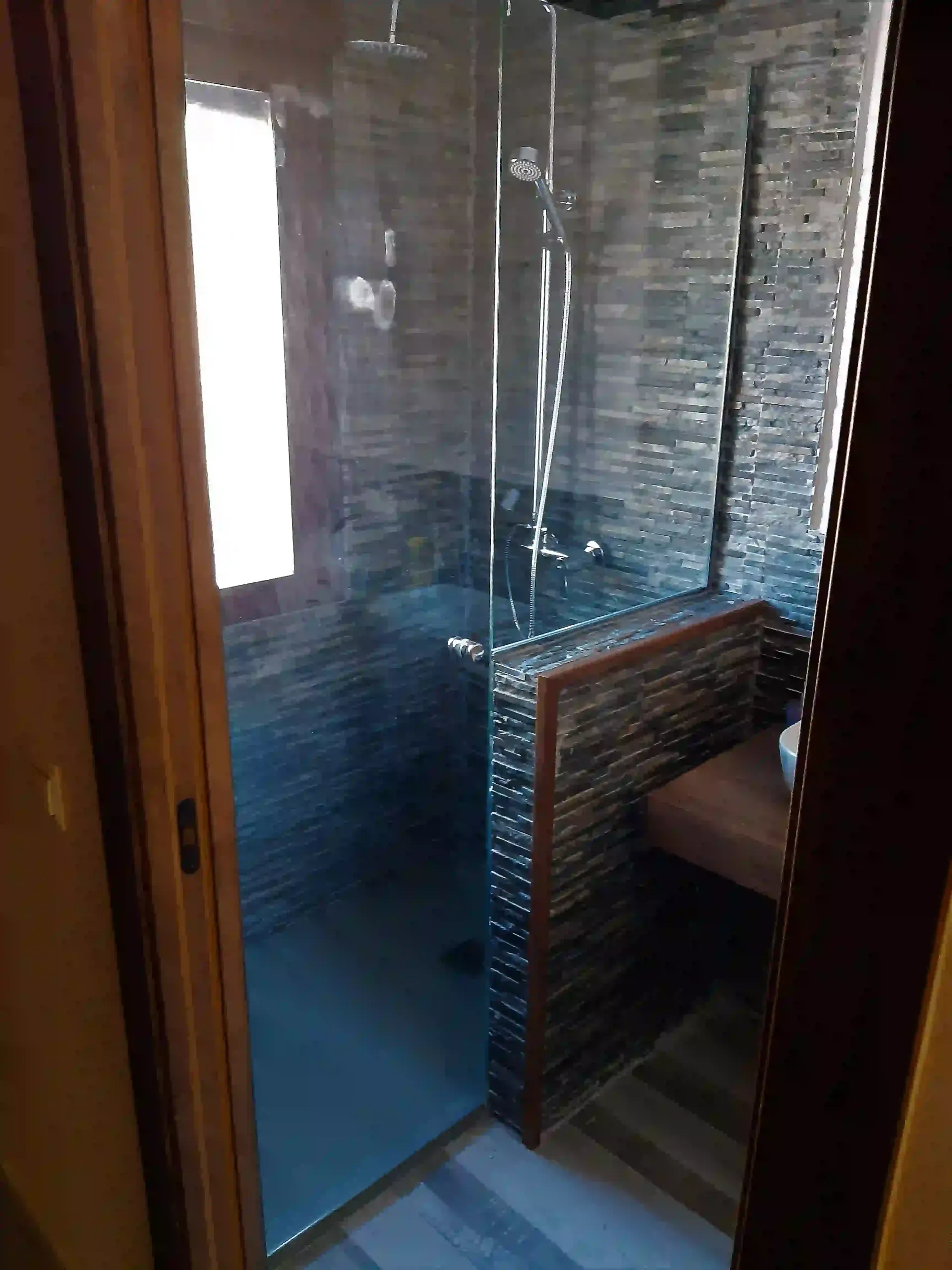 Un baño con ducha a ras de suelo y ventana.