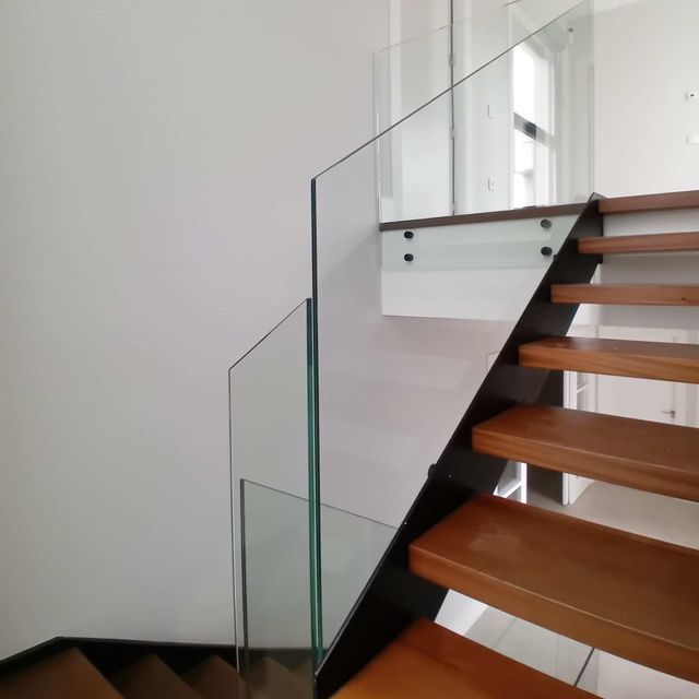 Una escalera con escalones de madera y barandilla de cristal.