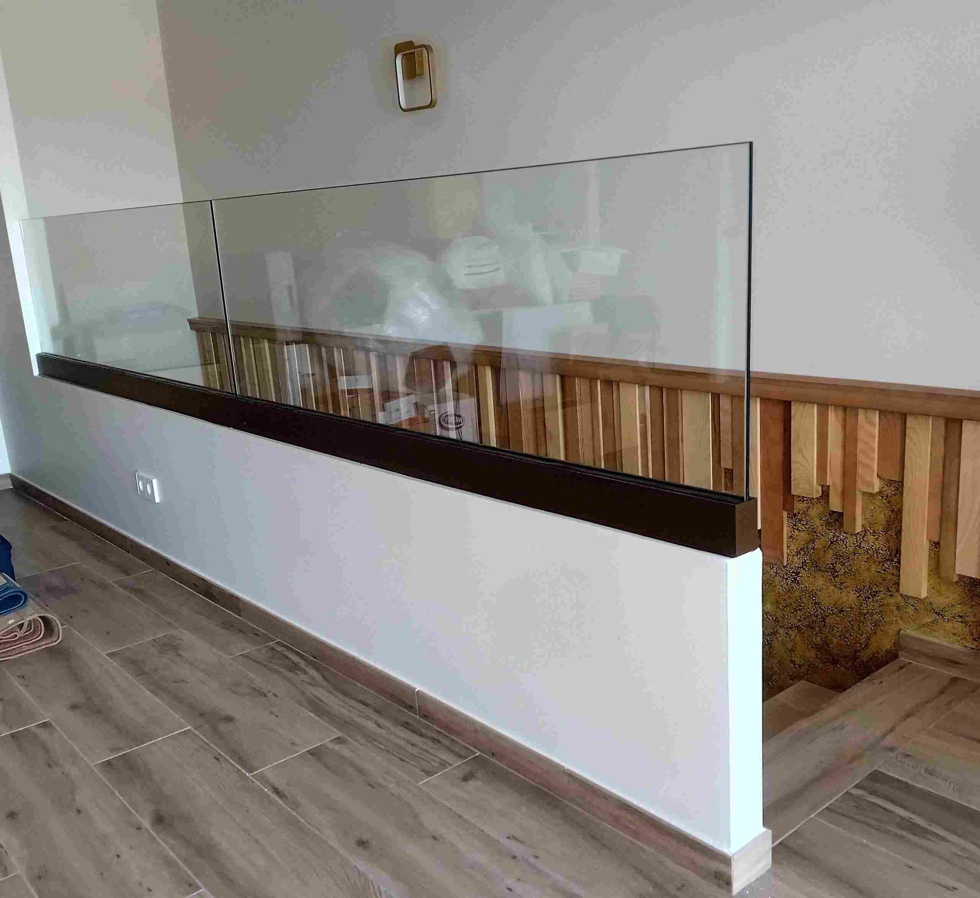 Una escalera con barandilla de cristal y barandilla de madera.