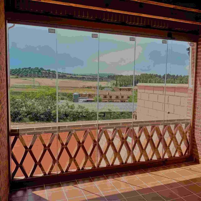 Un balcón con puertas corredizas de vidrio y barandilla de madera.
