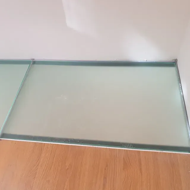 Un trozo de vidrio reposa sobre un piso de madera.