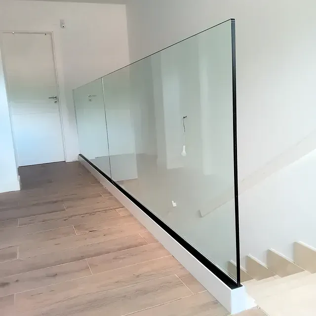 Una escalera con barandilla de cristal y suelo de madera.