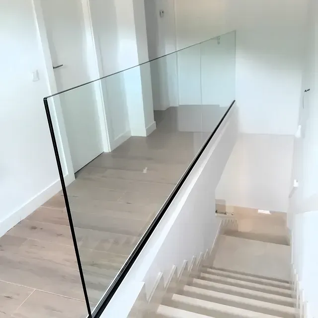 Una escalera con barandilla de cristal y suelo de madera.