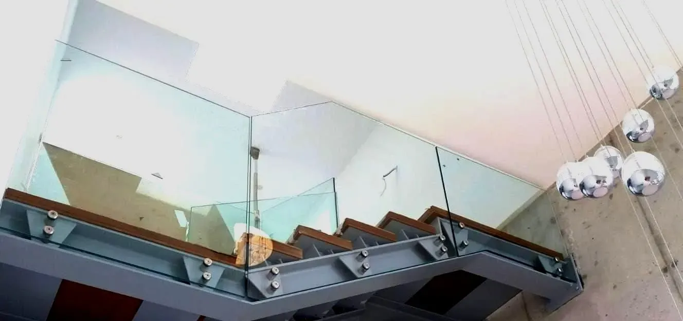Una escalera con barandilla de cristal en un edificio.
