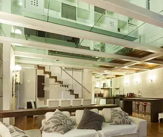 Una sala de estar con un sofá y escaleras al fondo.