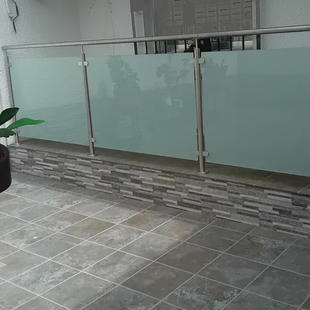 Un balcón con barandilla de cristal y una planta en una maceta.