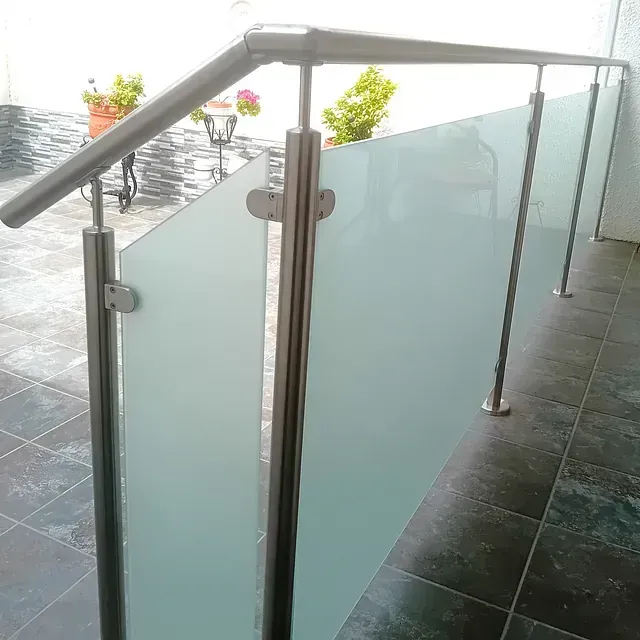 Una barandilla de acero inoxidable con paneles de vidrio esmerilado en un balcón.