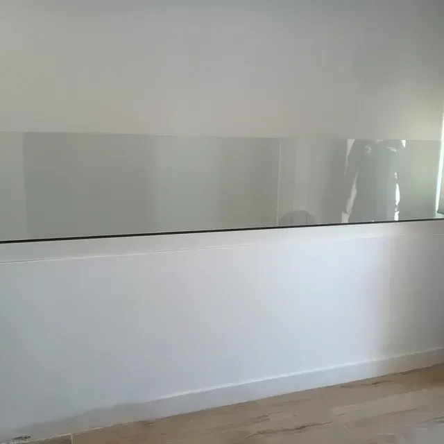 Una habitación con barandilla de cristal y una pared blanca.